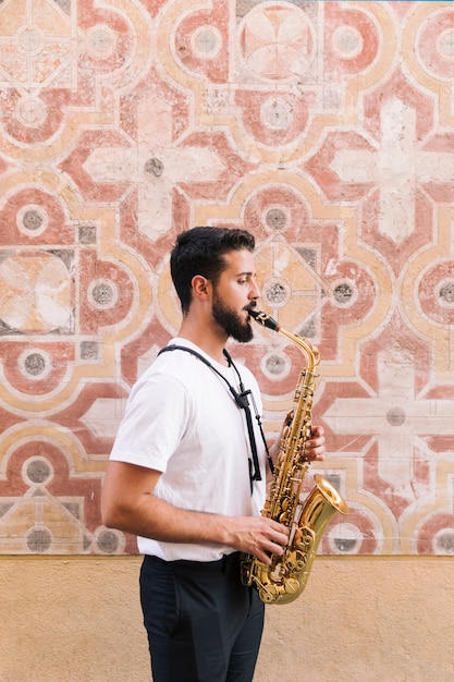 Free Photo sideways man medium shot playing the saxophone with geometric background