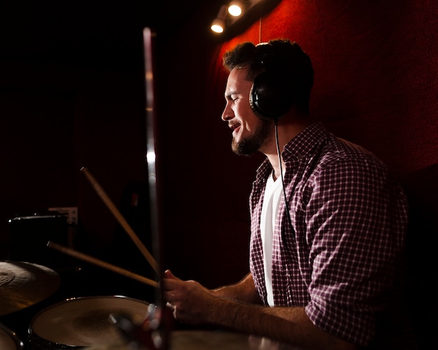 Sideways man playing drums and wearing headphones