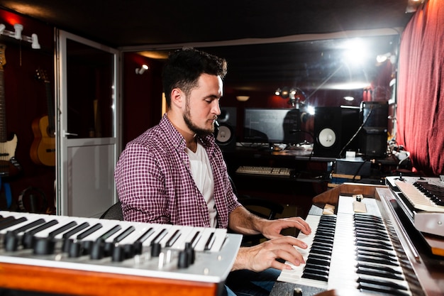 Free photo sideways man playing the keyboard in the studio