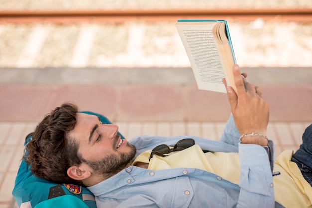 Free photo sideways man reading a book on train staion