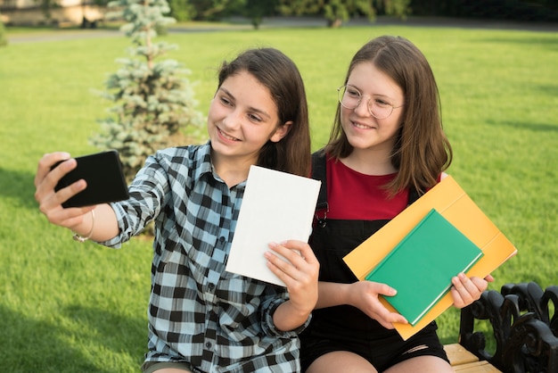 Free photo sideways medium shot of teenage girls taking a selfie