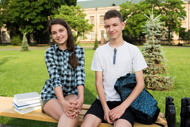 Free photo sideways medium shot of teenagers sitting on bench