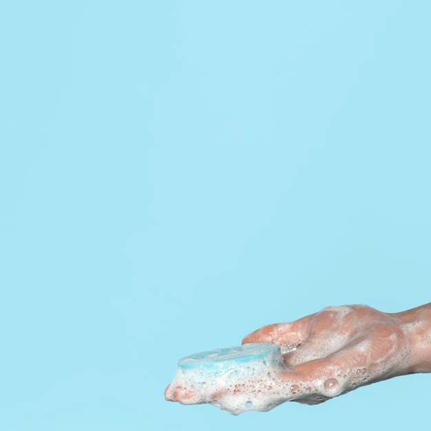 Sideways person holding a blue soap with copy space