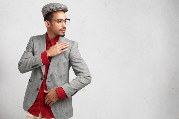 Free photo sideways portrait of intelligent male researcher or scientist wears cap, red shirt and formal jacket,