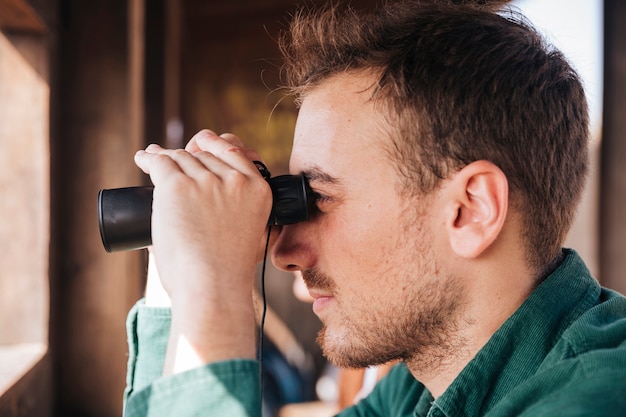 Sideways portrait of a man looking through binoculars