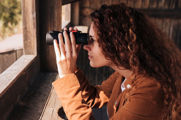 Free Photo sideways redhead woman looking through binoculars