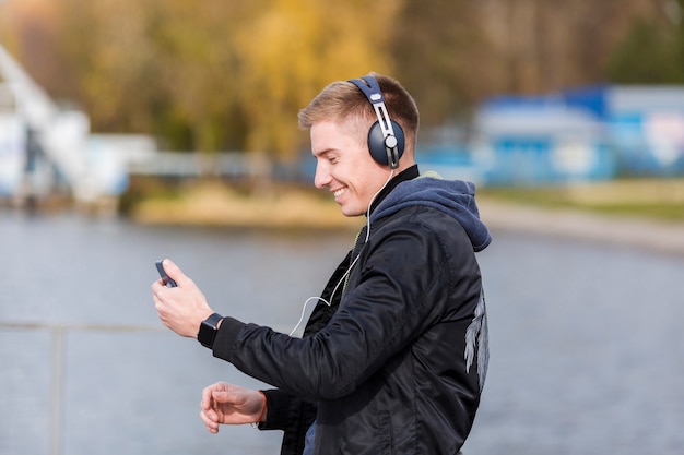 Sideways smiley blonde man listening to music outside