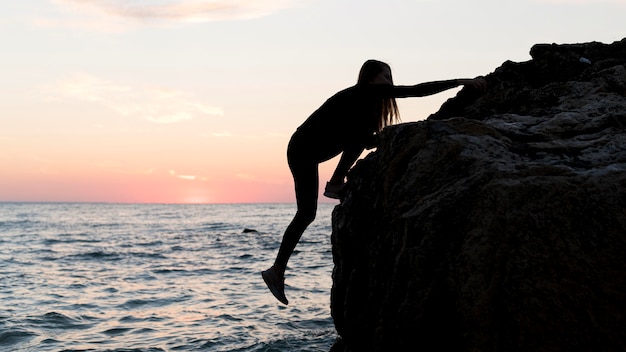 Free Photo sideways woman climbing on a rock