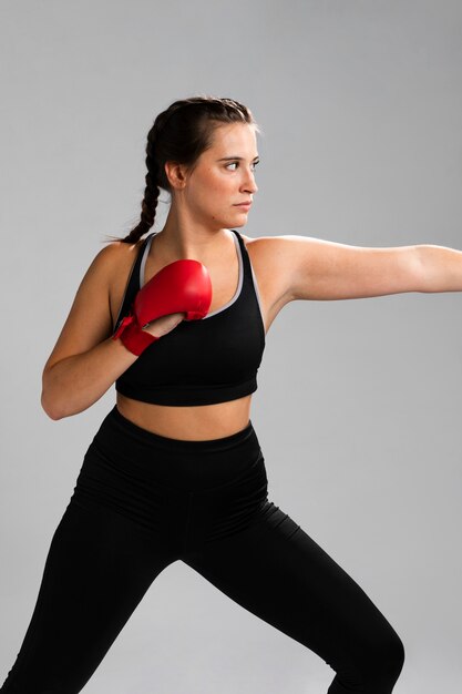 Sideways woman dressed in fitness clothes ready to give a punch