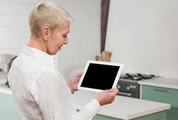 Free photo sideways woman looking on her tablet