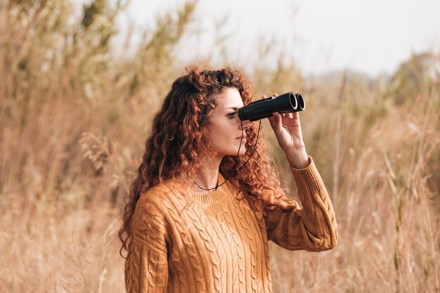 Sideways woman looking through binoculars