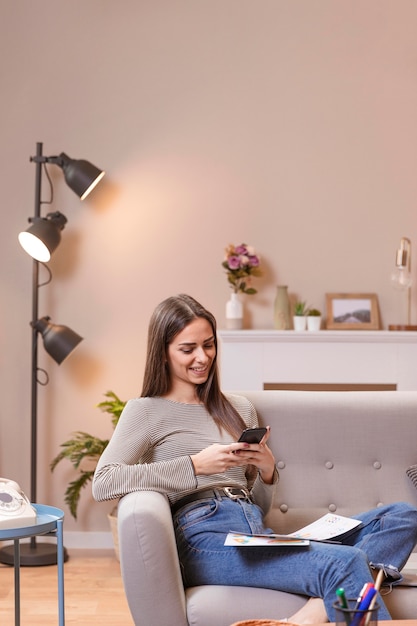 Free Photo sideways woman sitting on couch and works on her phone