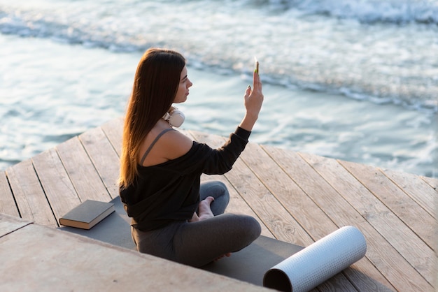 Sideways woman taking a photo of the sea