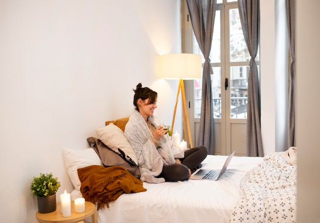 Free photo sideways woman watching a tv show on the laptop