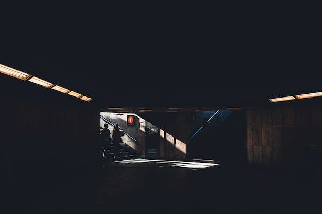 Free Photo silhoette of two people entering a dark shady underground building