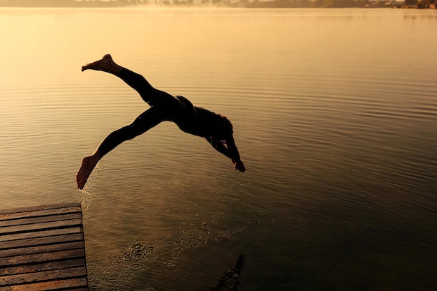 Free Photo silhouette of active sportsman dashing into foggy lake