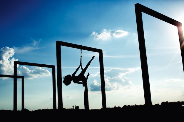 Silhouette of aerial silk dance at rooftop at sunset