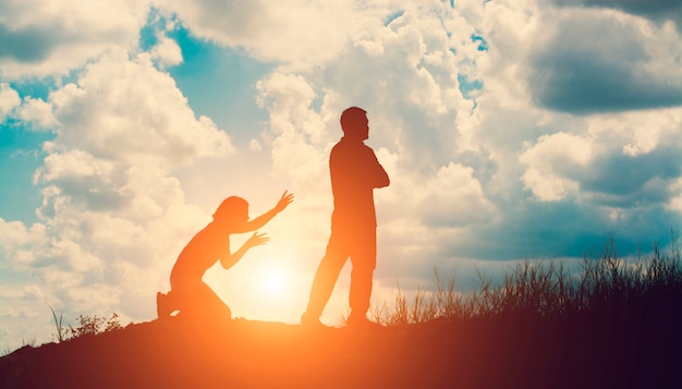 Silhouette of angry man with his wife kneeling