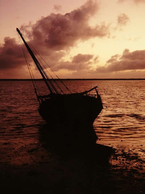 Silhouette of a boat on a shore near the water under a pink sky at Lamu, Kenya