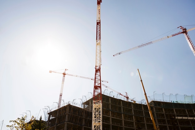 Free photo silhouette of buildings under construction against blue sky in sunlight