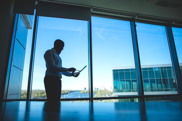 Free photo silhouette of a business man in front of a window