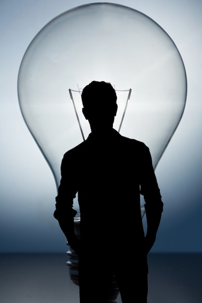 Free Photo silhouette of businessmen with a lightbulb background