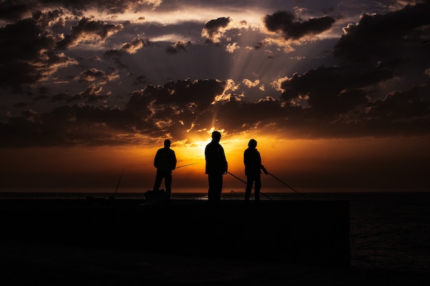 Free Photo silhouette of fisher on the beach at sunset