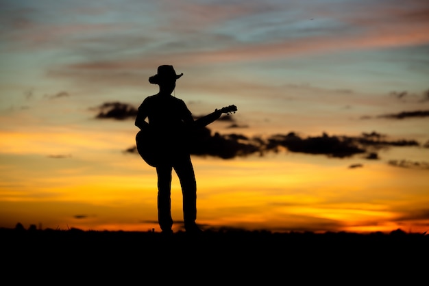 Silhouette girl guitarist on a sunset