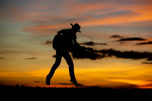 Silhouette girl guitarist on a sunset