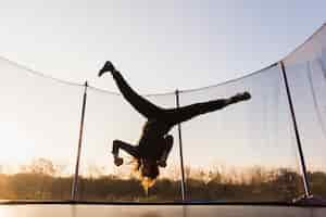 Free photo silhouette of girl jumping on a trampoline doing split