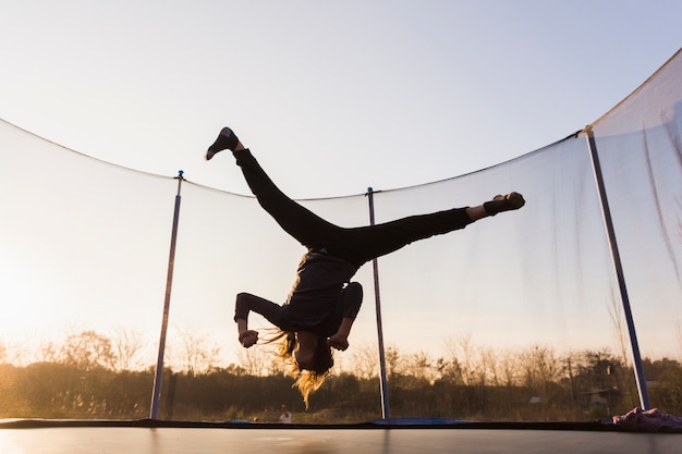 Silhouette of girl jumping on a trampoline doing split