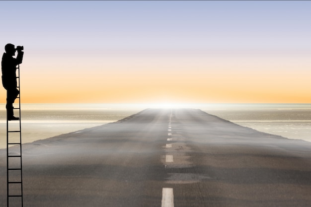 Free photo silhouette on a ladder with road background