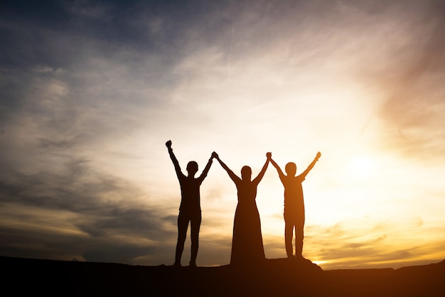 Silhouette of mother with her daughter standing and sunset