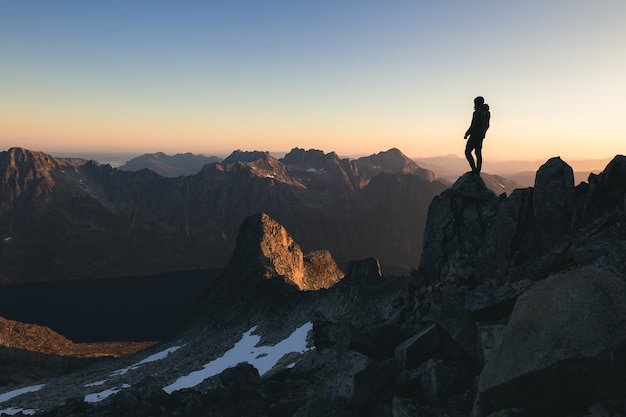 Silhouette of a person standing on the top of a hill under the beautiful colorful sky in the morning