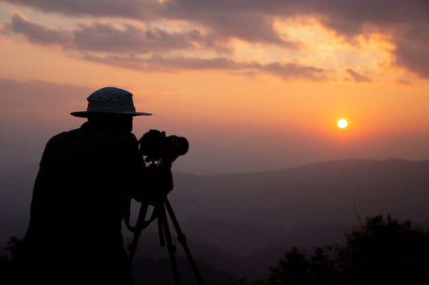 Free photo silhouette of a photographer who shoots a sunset in the mountains