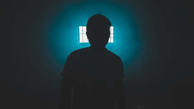 Free Photo silhouette of standing person in a dark room