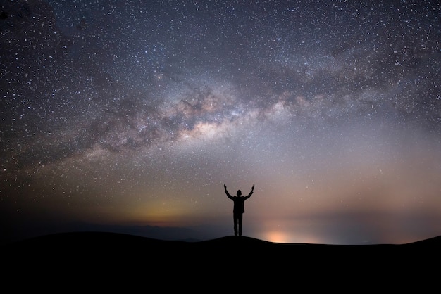 Free Photo silhouette successful man on the top of the hill on a background with stars