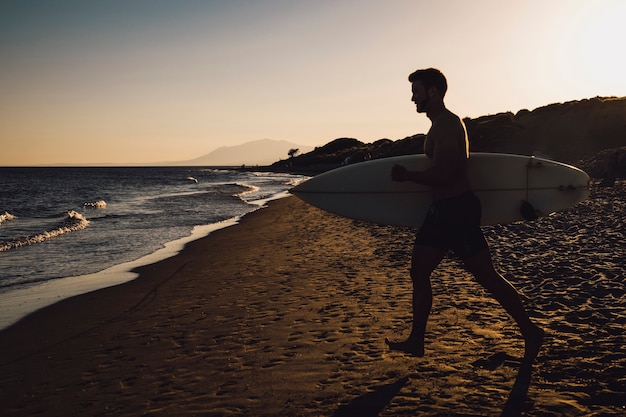 Silhouette of surfer walking towards the sea