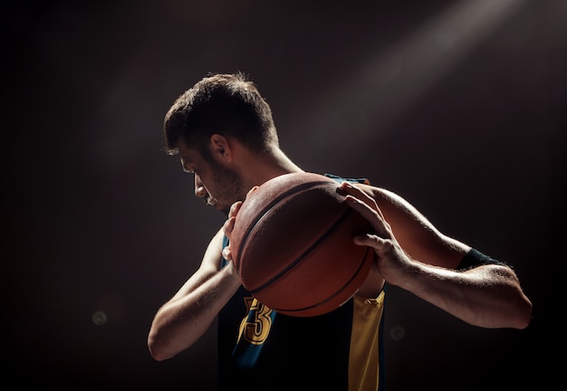 Silhouette view of a basketball player holding basket ball on black space