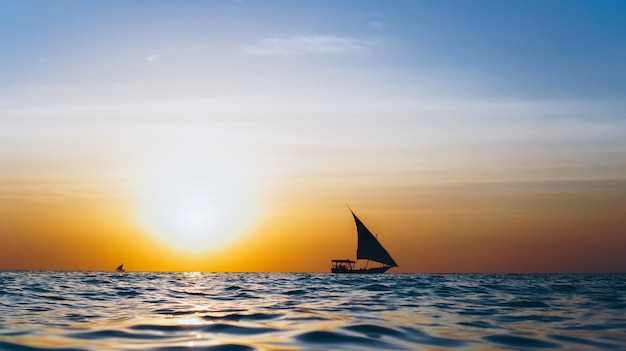 Free Photo silhouette of yacht in the open ocean on the sunset