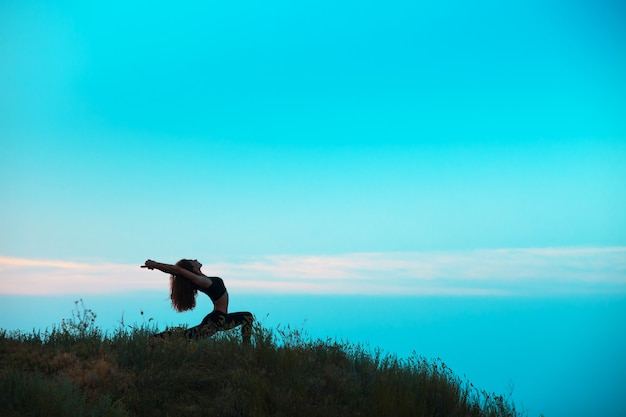 The silhouette of young woman is practicing yoga