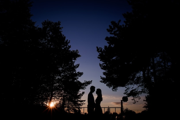 Silhouettes of a couple standing in the evening lights