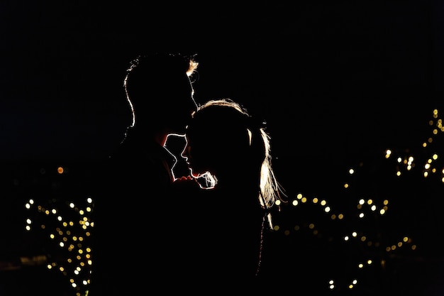 Silhouettes of a lovely young couple standing on the rooftop in the night