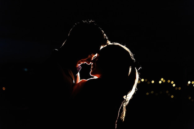 Silhouettes of a lovely young couple standing on the rooftop in the night