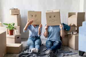 Free photo silly couple at home on moving day with boxes over head