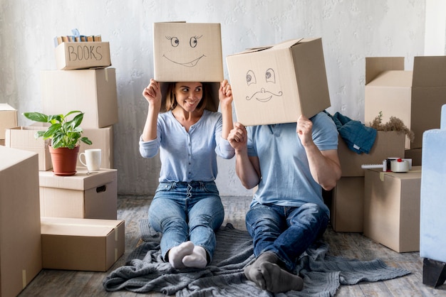 Free photo silly couple with boxes over heads at home on moving day