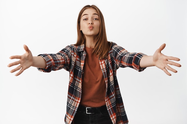 Silly and cute girlfriend reaching for kiss and hugs, stretching out hands and pucker lips, kissing someone, clinge onto someone, standing against white background