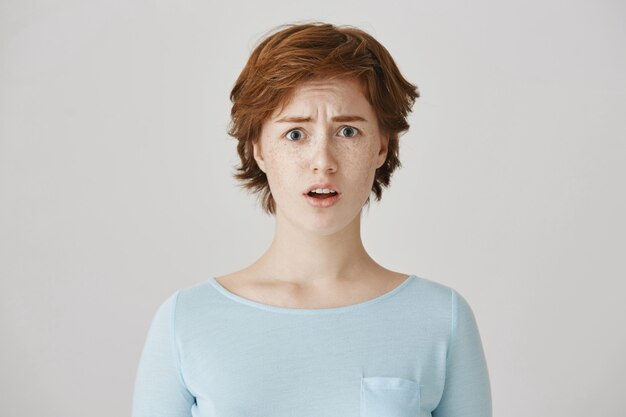 Silly cute redhead girl posing against the white wall