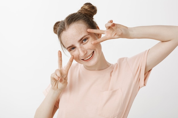 Silly and happy beautiful redhead teenage girl posing against the white wall