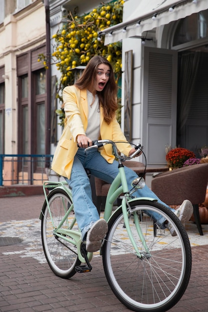 Free photo silly woman riding her bike outdoors in the city